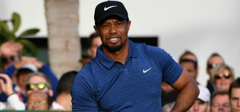 Tiger Woods is wearing a blue shirt and hat as he is on a golf course.