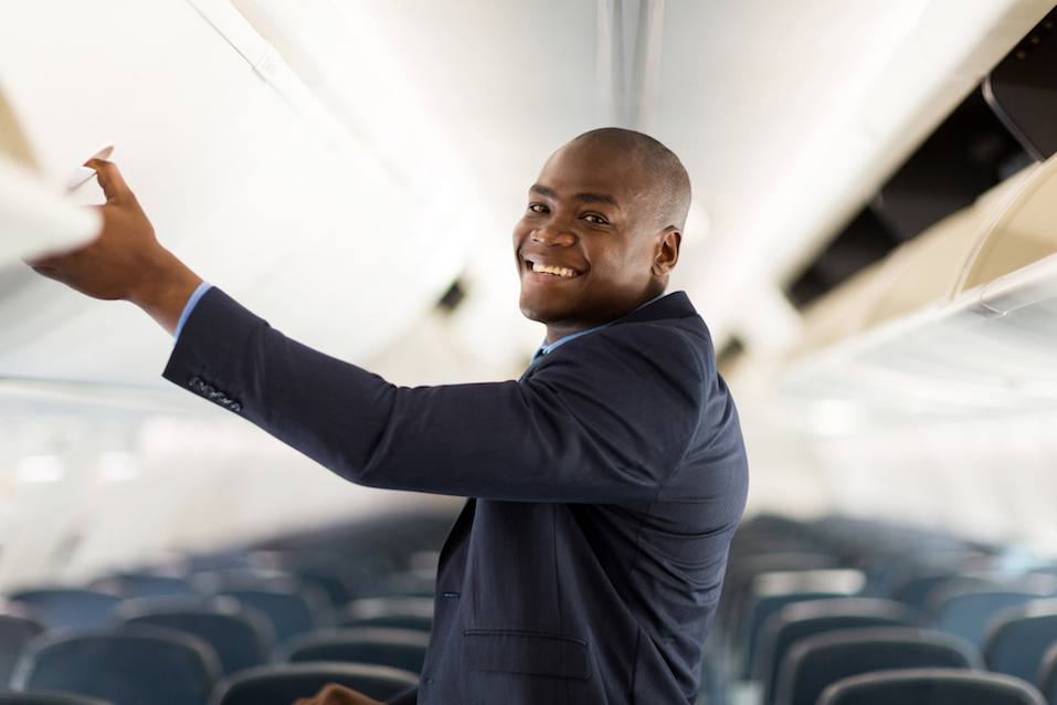 businessman opening overhead locker on airplane