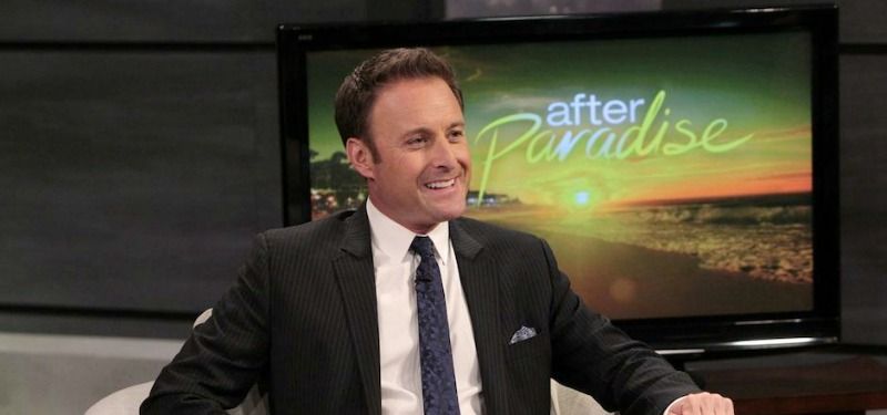 Chris Harrison is in a suit and smiling in front of a TV that says "After Paradise."