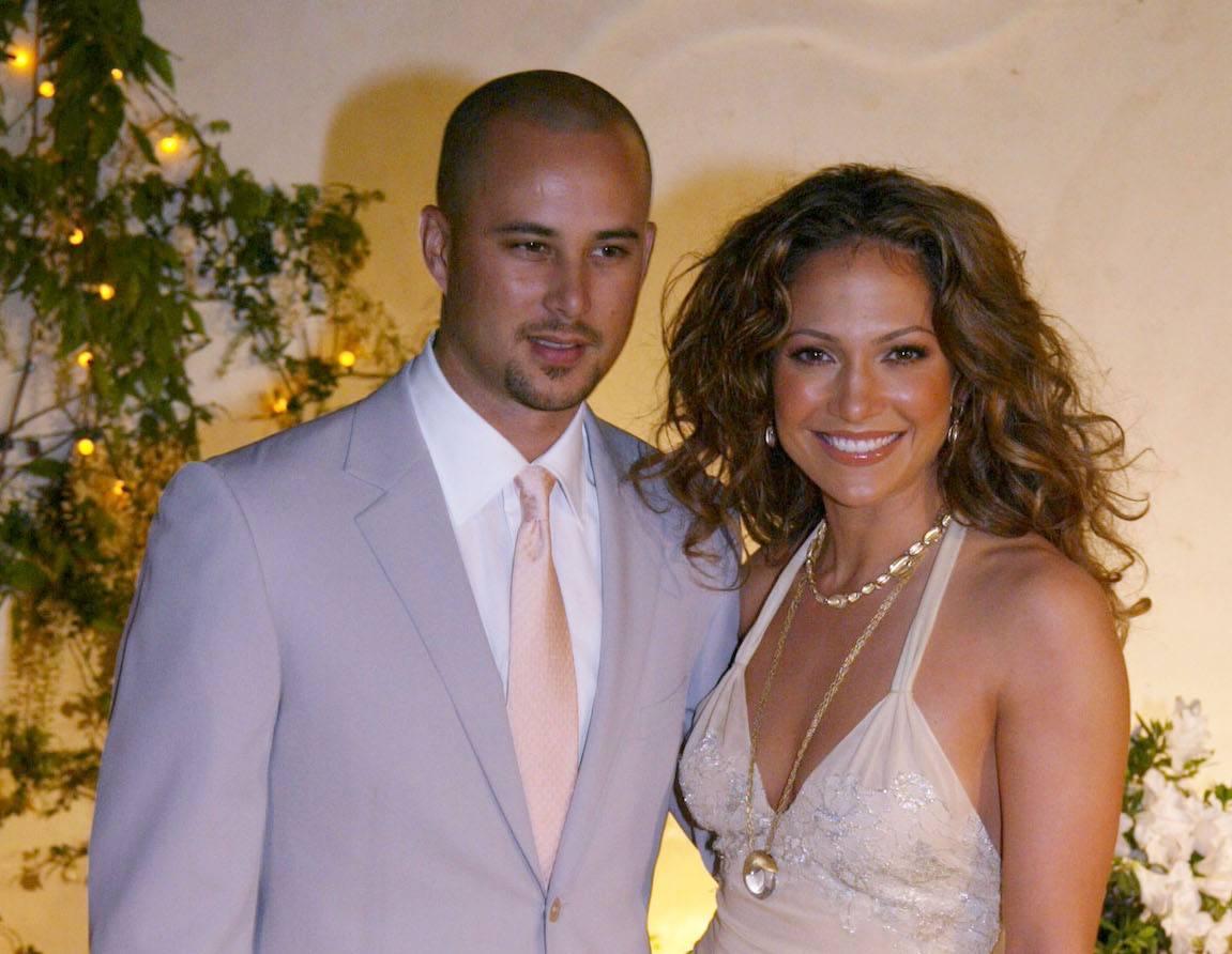 Jennifer Lopez poses and smiles with then-husband Cris Judd at a restaurant opening in 2002.