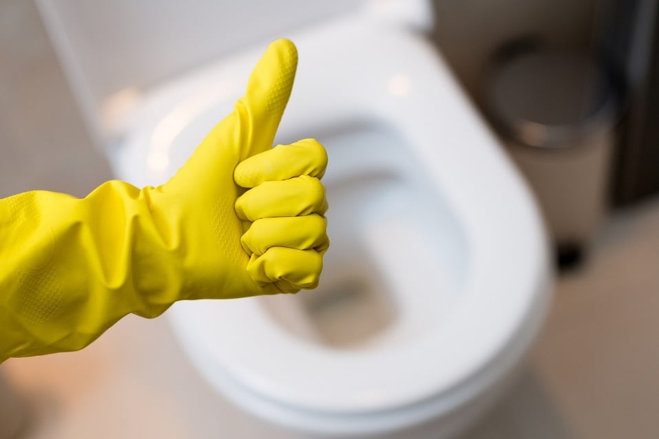 hand with yellow protective rubber glove over toilet