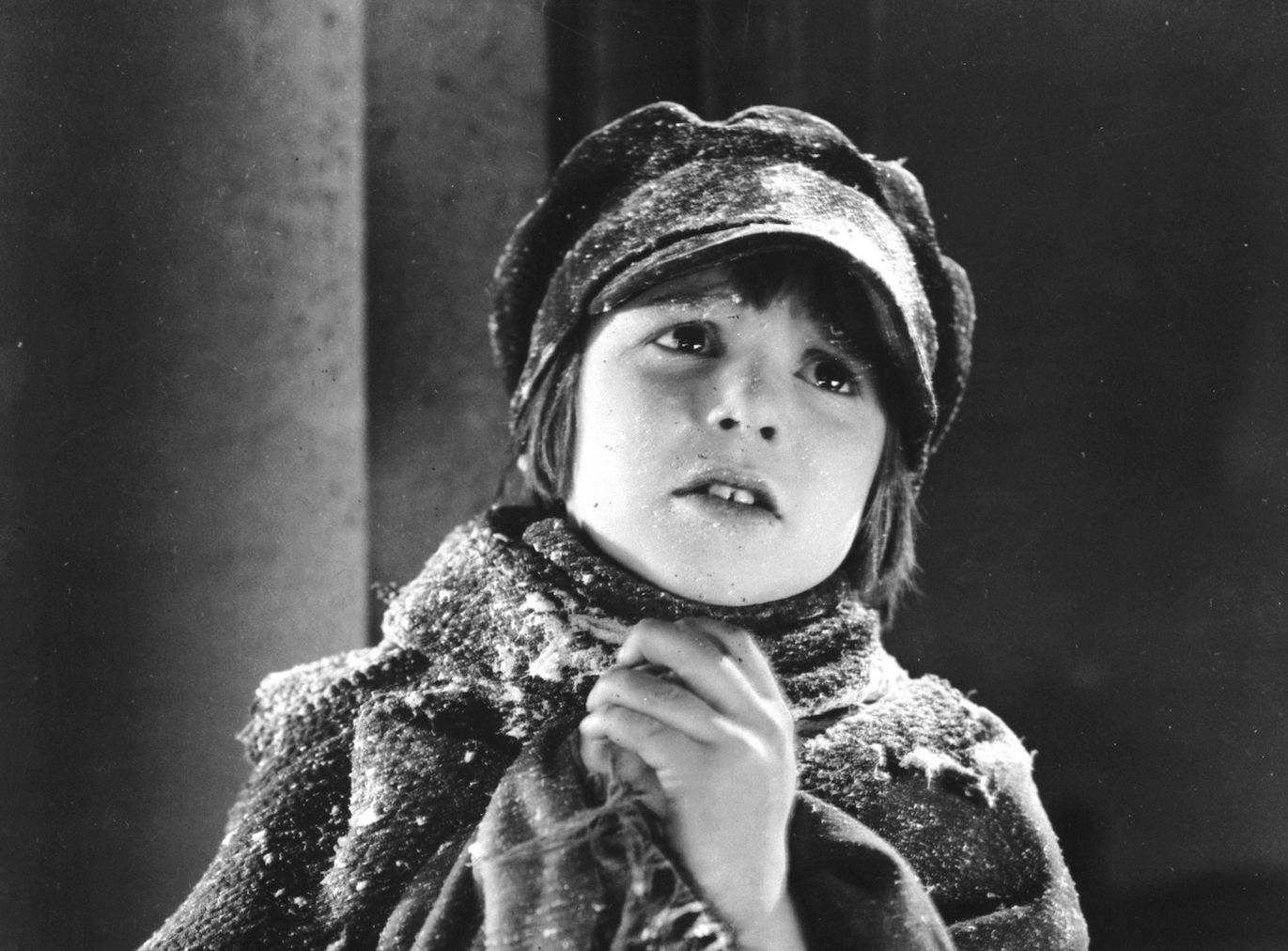 Jackie Coogan wearing winter clothes covered in snow in black and white