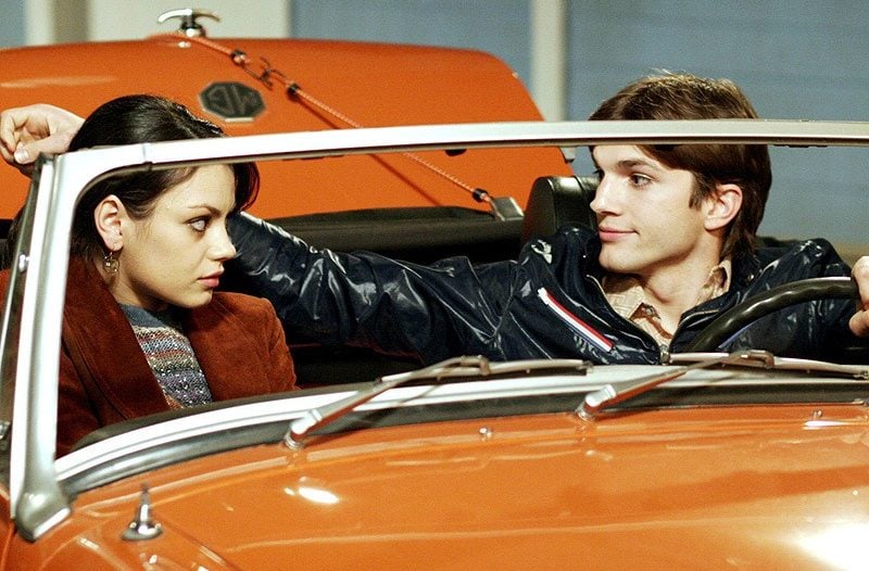 Mila Kunis and Ashton Kutcher sit in an orange car on That '70s Show