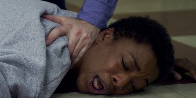 Poussey is being crushed on the ground under an officer.