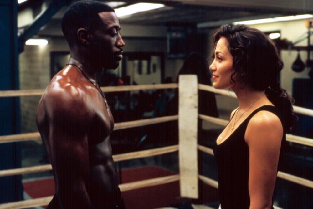 Wesley Snipes stands, shirtless, opposite Jennifer Lopez inside of a boxing ring in a scene from 'Money Train.'
