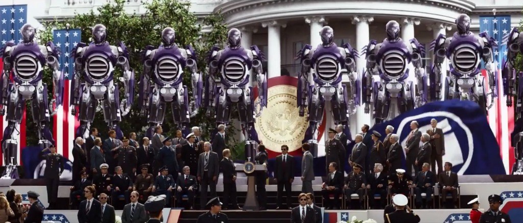 A row of giant robots lined up in front of the White House, surrounded by government officials