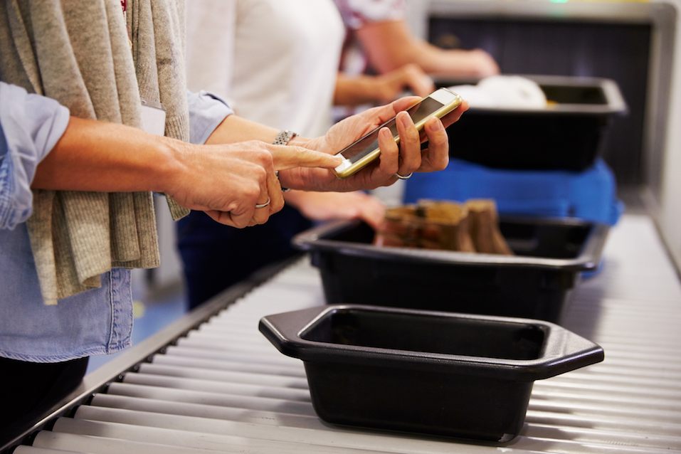 Man Checking Mobile Is Charged At Airport Security Check