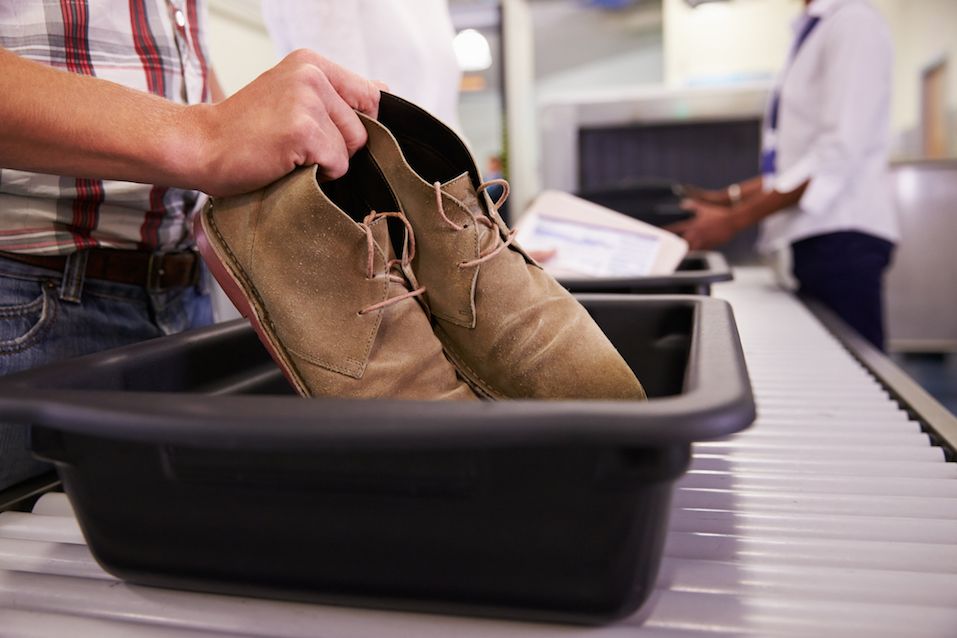 Man Putting Shoes Into Tray For Airport Security Check