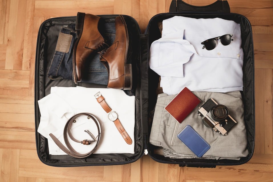 Open traveler's bag with men clothing and accessories