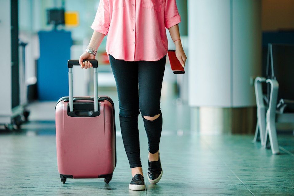 Passenger with passports and boarding pass and pink baggage