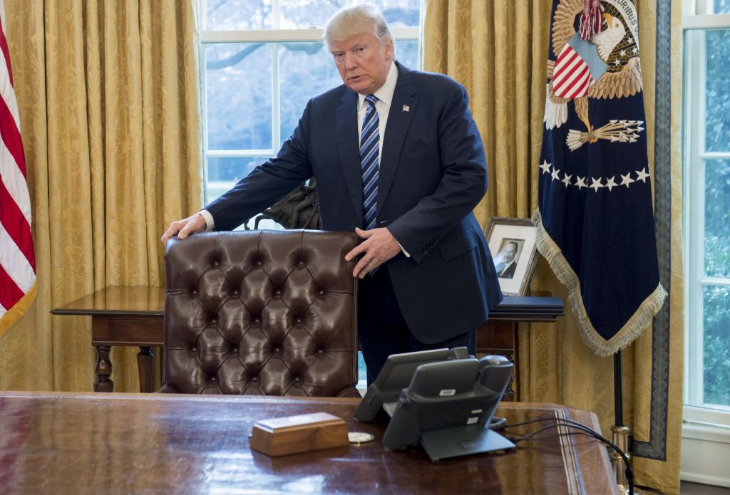 Donald Trump stands behind his desk