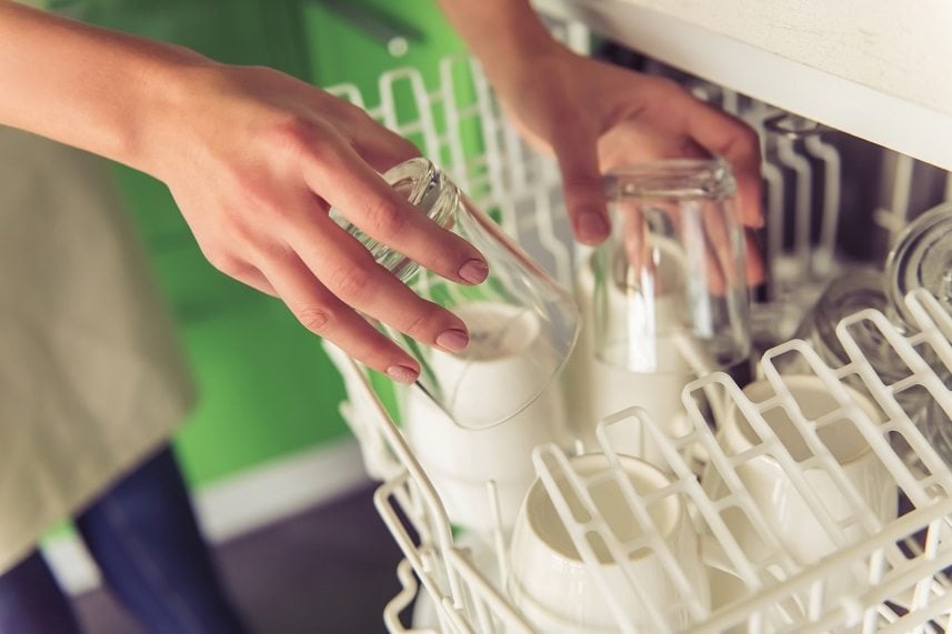 young woman putting dishes into dishwasher