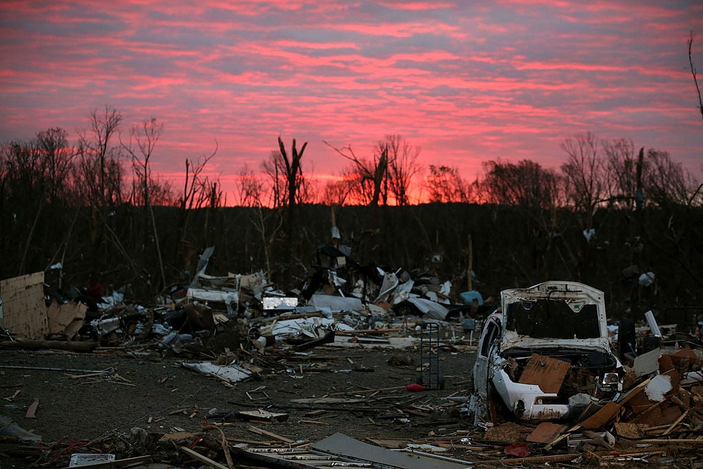 The sun rises behind debris that was left when a tornado hit Arkansas