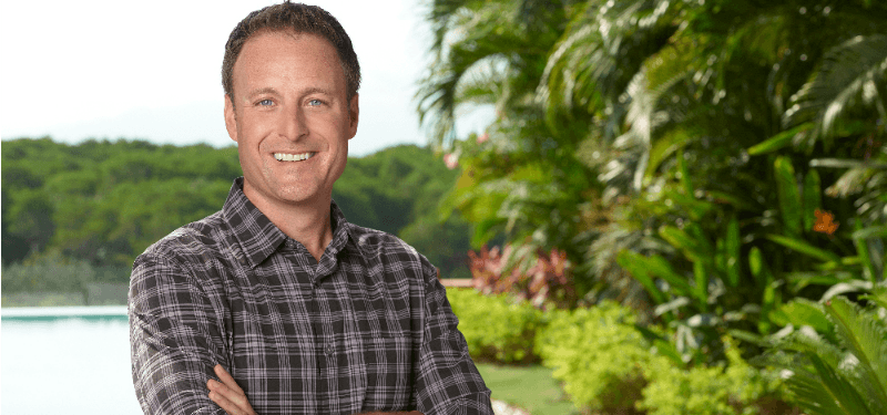 Chris Harrison is smiling with his arms crossed.