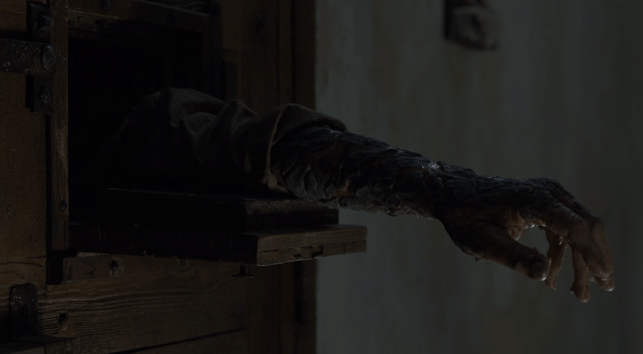 Jorah Mormont reaches an arm, covered in Greyscale, out of his cell door in a scene from the Season 7 'Game of Thrones' premiere.