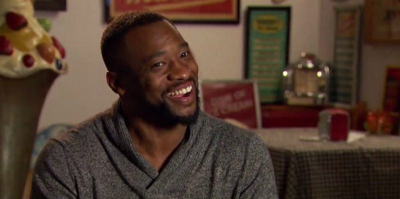 Kenny is smiling and wearing a sweater on The Bachelorette.
