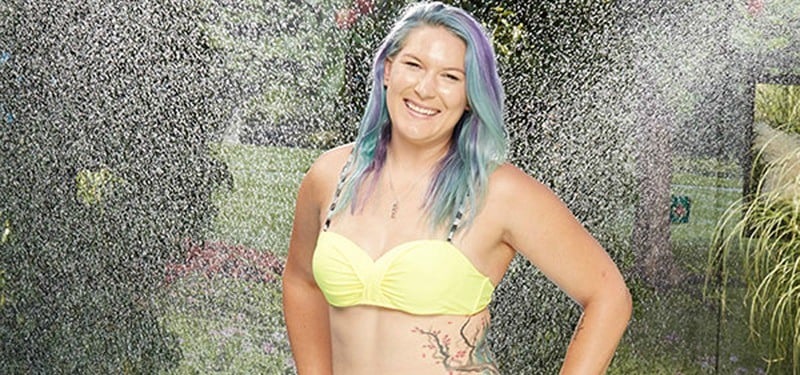 Megan Lowder smiles in a yellow bikini as water is being sprinkled all over her.