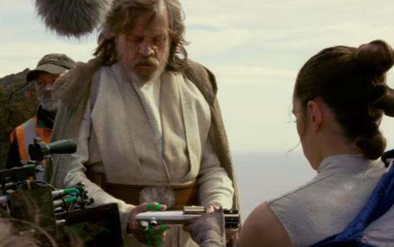 Rey hands Luke his old lightsaber. 