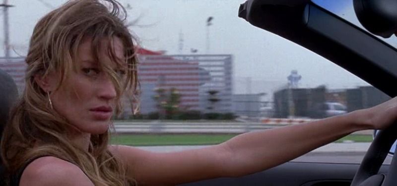Gisele Bündchen is looking to the side as she drives a convertible. 