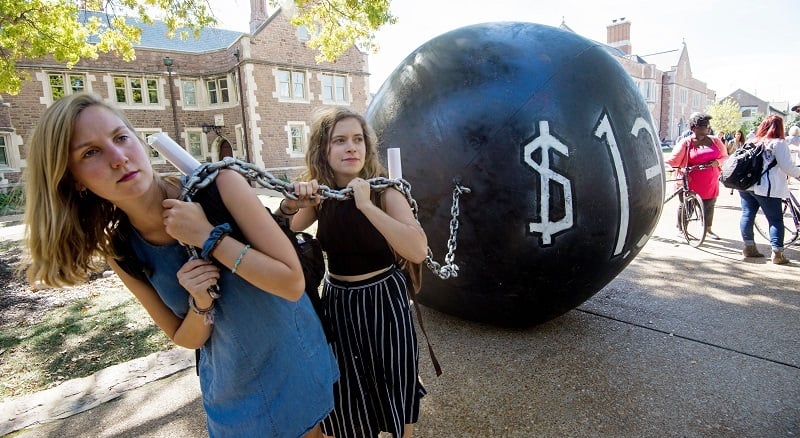 Students pull a mock ball and chain representing the outstanding student debt and price of student loans