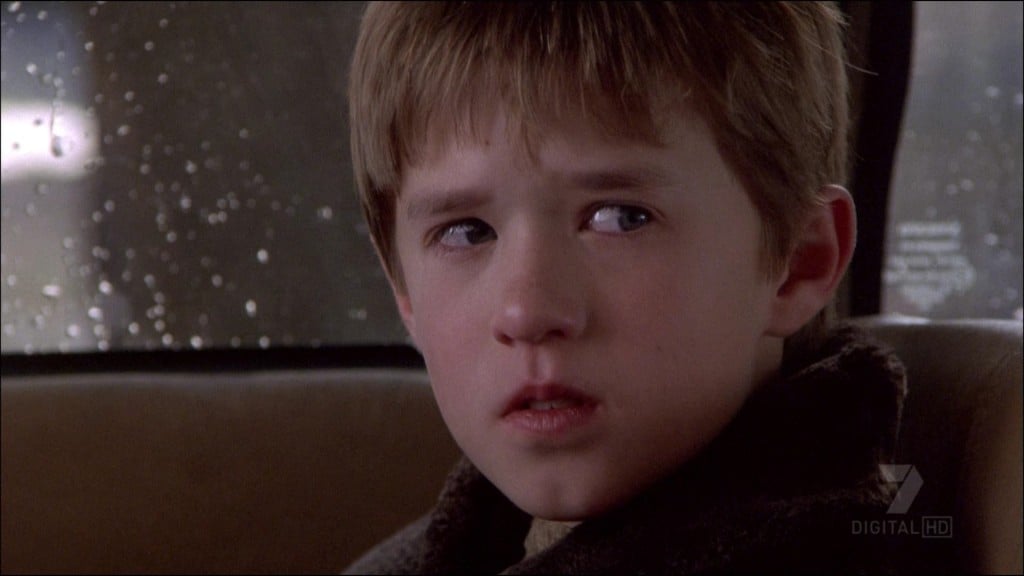 A young Haley Joel Osment sits in the back of a car in The Sixth Sense