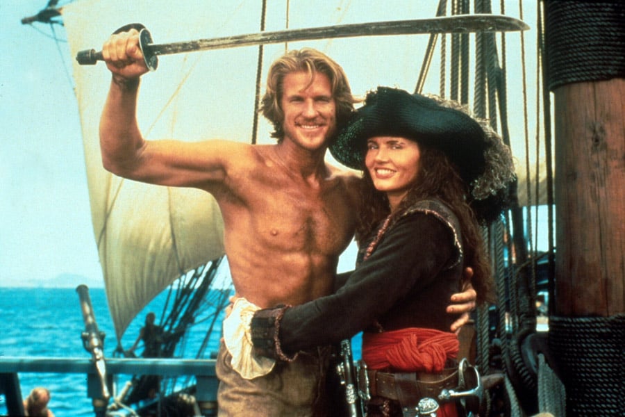 A man with his shirt off and a girl dressed as a pirate in Cutthroat Island pose for a photo