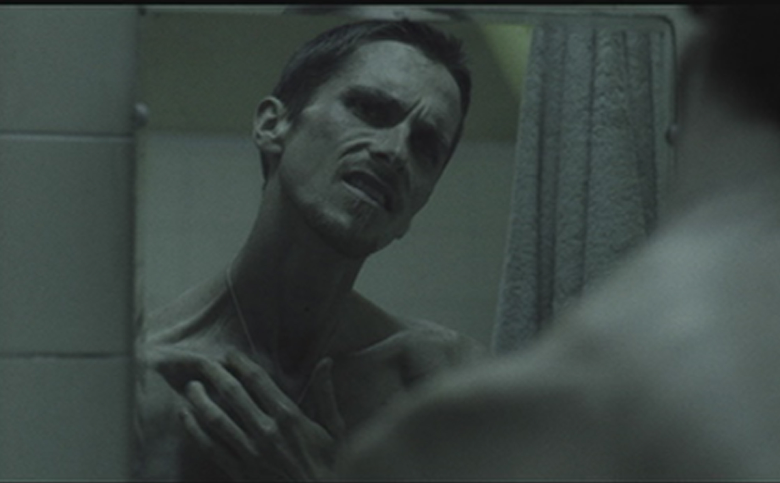 A shirtless, gaunt Christian Bale glowers into a mirror