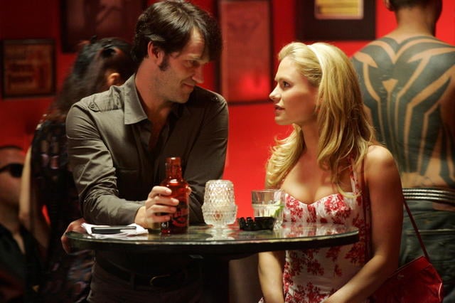 Stephen Moyer as Bill Compton and Anna Paquin as Sookie Stackhouse talking at a table on True Blood 