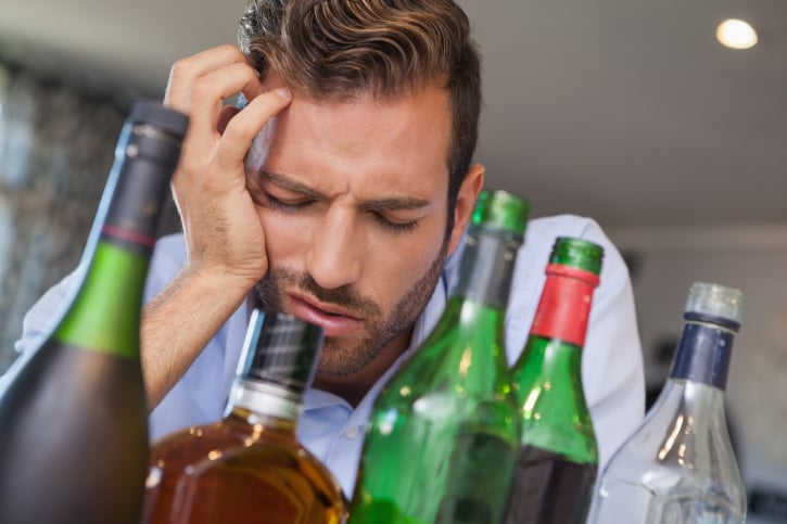 hungover man surrounded by alcohol
