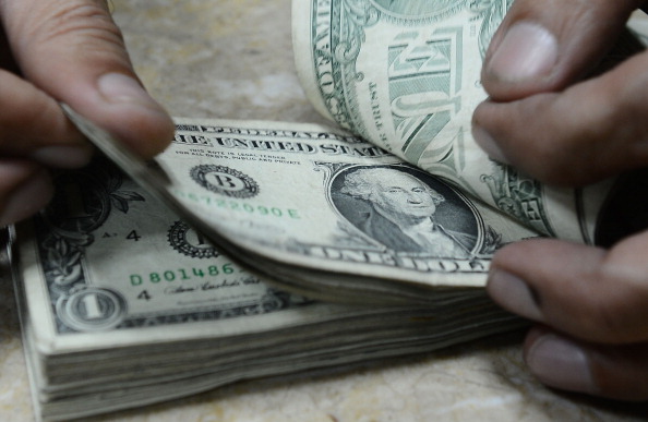 a man flipping through a stock of US dollars bills