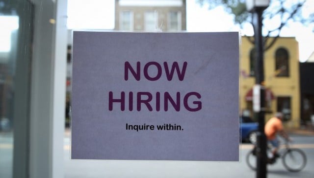 A now hiring sign in a window