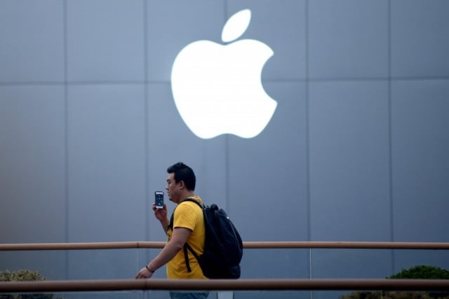 A man uses a mobile phone as he walks past an Apple store in Beijing on April 14, 2014.