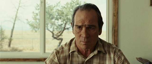 Tommy Lee Jones sits in front of a window in No Country for Old Men