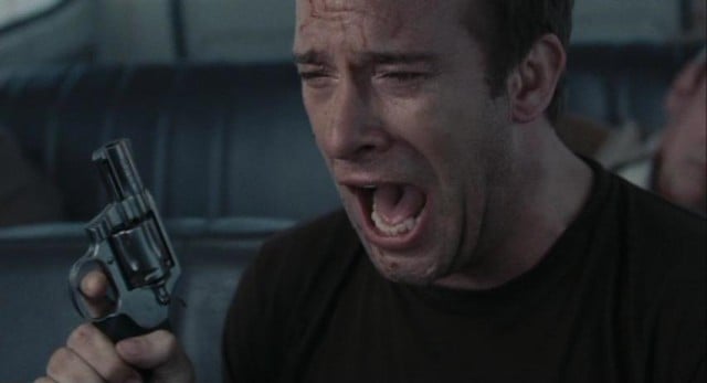 Thomas Jane yells while holding up a gun in a scene from The Mist