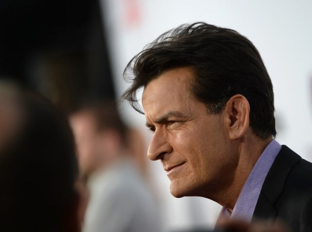 Charlie Sheen speaking with other guests at an event.