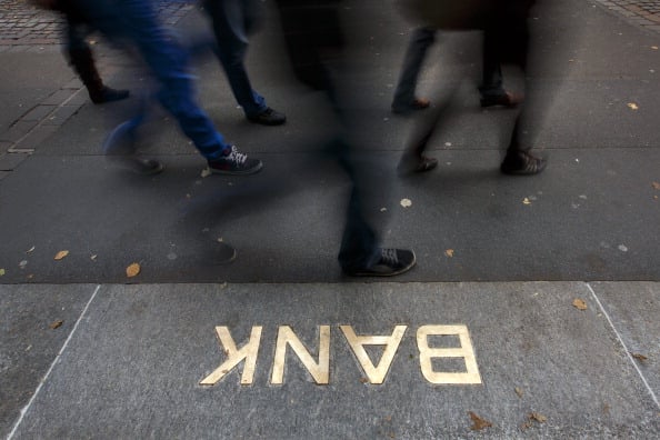 Pedestrians walk past an embossed Bank sign at the entrance of a branch of the Swiss banking giant UBS on October 13, 2012 in Zurich. UBS could shed 10,000 jobs in the near future, according to a report in the Tages Anzeiger daily. The company could announce the layoffs when it presents its quarterly results on October 30, the newspaper said. (Photo by Afabrice Cofrini/AFP/Getty Images)