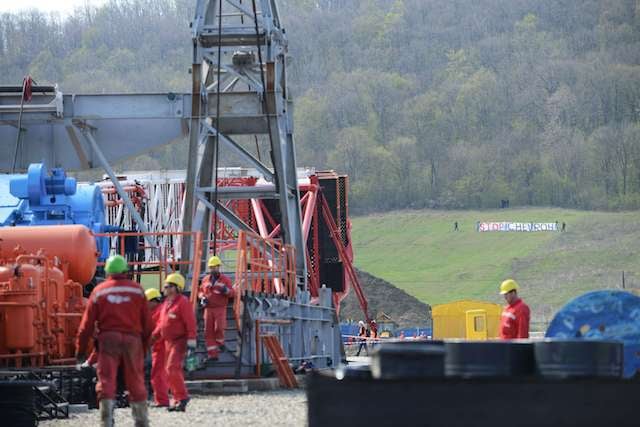 Chevron workers are seen with protesters in the distance