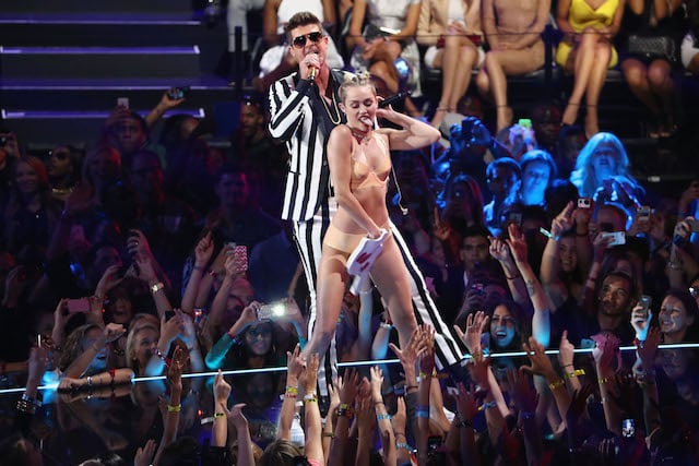 Miley Cyrus is dancing on Robin Thicke on stage.
