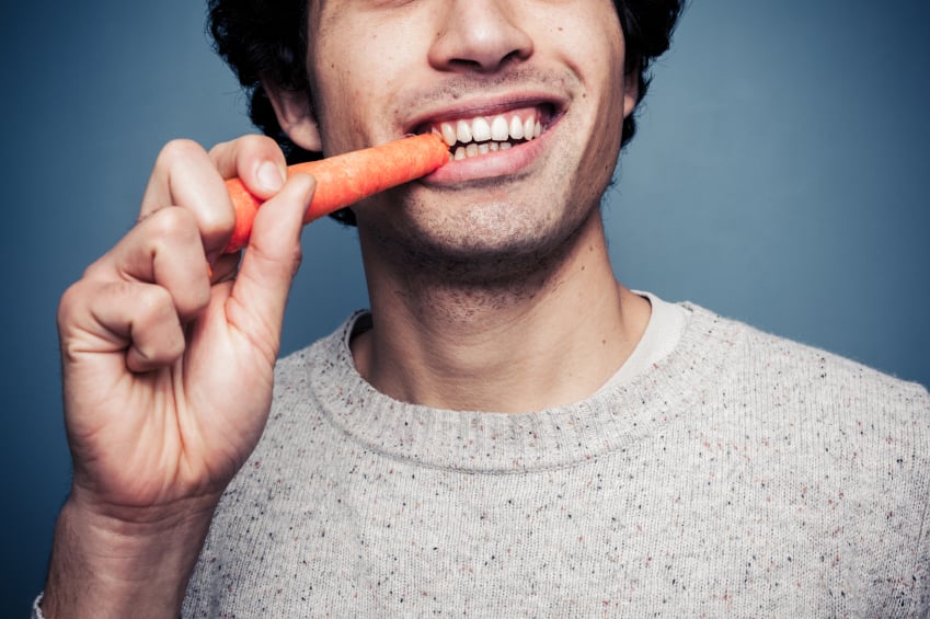 A man chows down on a carrot A man chows down on a carrot