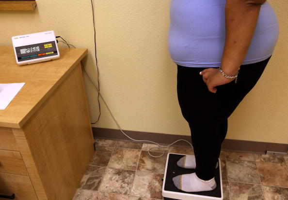 Women weighing her weight in a doctor's room