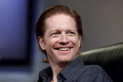 Actor Eric Stoltz smiles while sitting in a black chair