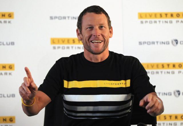 Lance Armstrong sitting and speaking as she gestures with a finger. Lance Armstrong sitting and speaking as she gestures with a finger.