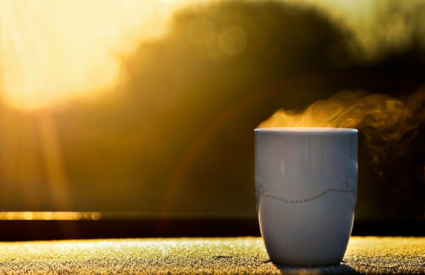 steaming mug of coffee in front of a window