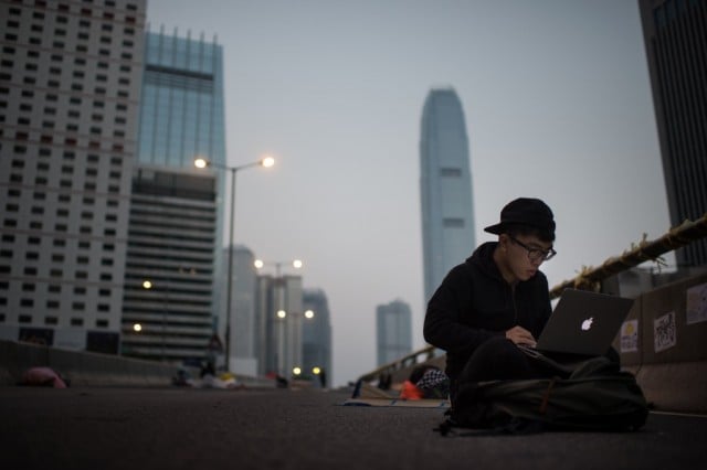 A pro-democracy protester using a laptop computer as he sits on an occupied road in the Admiralty district of Hong Kong early on October 8, 2014