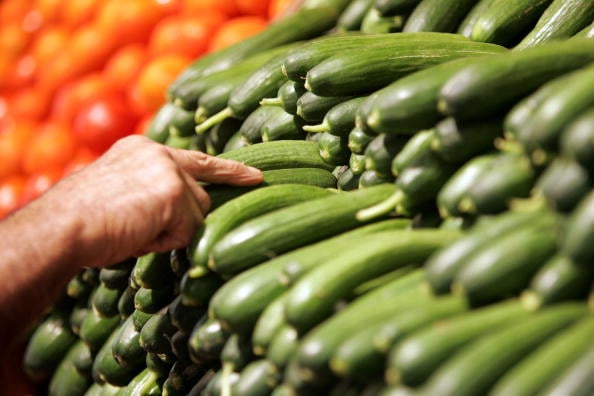A person looks at green zucchinis at a supermarket grocery section. A person looks at green zucchinis at a supermarket grocery section.