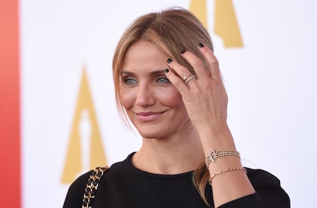 Cameron Diaz brushes away her hair while smiling on a red carpet. 