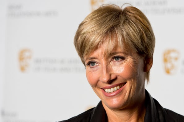 Emma Thompson smiling for photographers while standing on a red carpet.