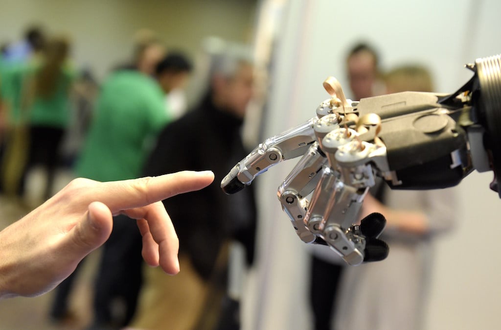 A man moves his finger toward SVH (Servo Electric 5 Finger Gripping Hand) automated hand made by Schunk during the 2014 IEEE-RAS International Conference on Humanoid Robots in Madrid on November 19, 2014. The conference theme "Humans and Robots Face-to-Face" confirms the growing interest in the field of human-humanoid interaction and cooperation, especially during daily life activities in real environments. Photo by Gerard Julien/AFP/Getty Images.