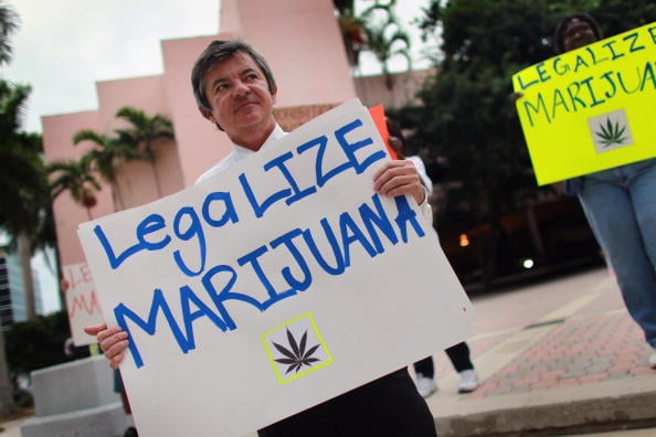 Florida Attorney General candidate Jim Lewis, who is running on a platform of legalizing marijuana, holds a sign during a campaign rally on October 12, 2010 in Fort Lauderdale, Florida (Photo source: Joe Raedle/Getty Images)