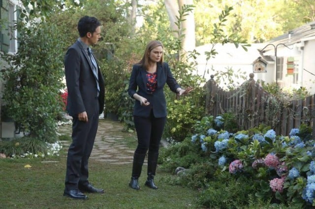 Two characters investigate a garden in front of a house.